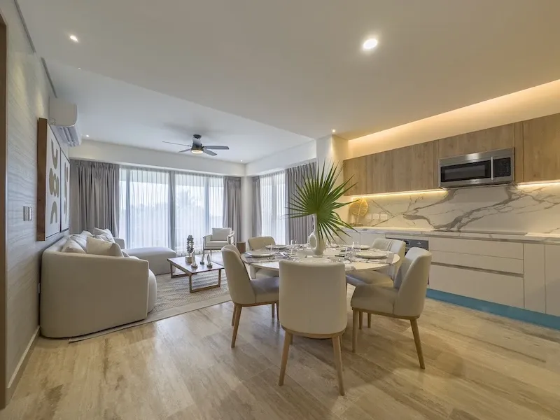 Sala-comedor de Sole BLU abierta a la cocina, con frente de mármol y ventilador de techo